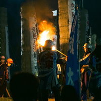 須賀川市の松明あかしで松明に点火を見守る法被姿の青年団の写真