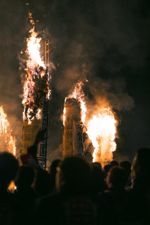 燃え上がる火柱に見入る松明あかしの見物客