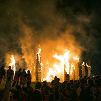 須賀川市の松明あかしで舞い上がる火柱の火花と見物人のシルエットの写真