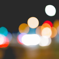 街の灯りがぼけて映る夜景、光の粒が浮かぶ夜間背景の写真