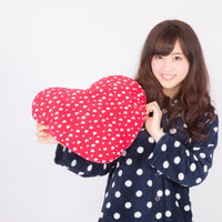 ハートのクッションを抱くパジャマ姿の女性の写真