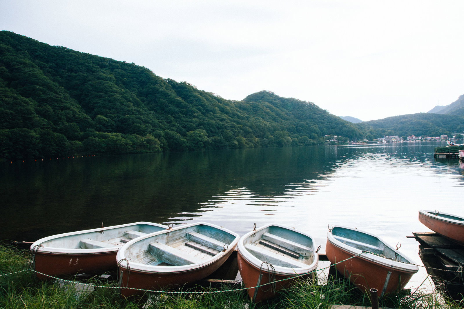 榛名湖の湖畔に並ぶ白いボートと緑の山々が映る風景