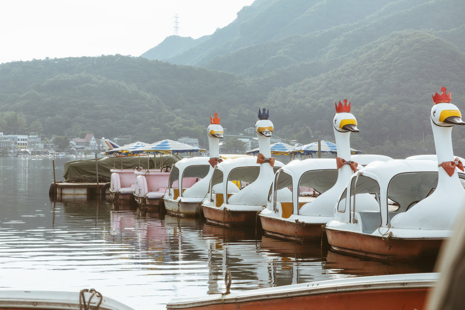 榛名湖に並ぶ白いスワンボートと背景の山々