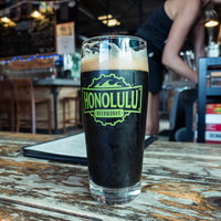 ホノルルのクラフトビールが木製テーブルに置かれた一杯の写真