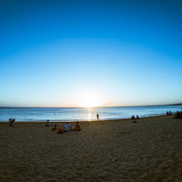 ハワイの砂浜でサンセットを眺める人々のシルエットの写真