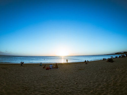 ハワイの砂浜でサンセットを眺める人々のシルエット