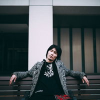 ベンチで悪態をつく黒いジャケットの男性の強面な表情の写真