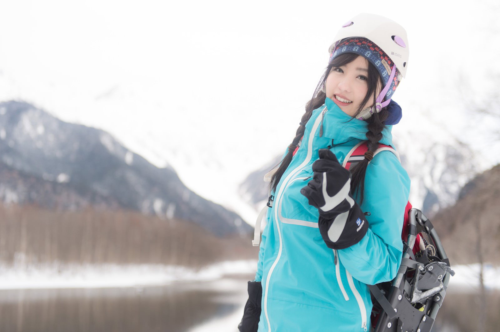 雪山でヘルメットとスキー板を持つ山ガール［モデル：河村友歌］