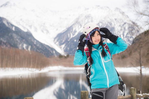 女性らしさを備えた登山用ヘルメットを着用し上高地の雪山で立つ女性