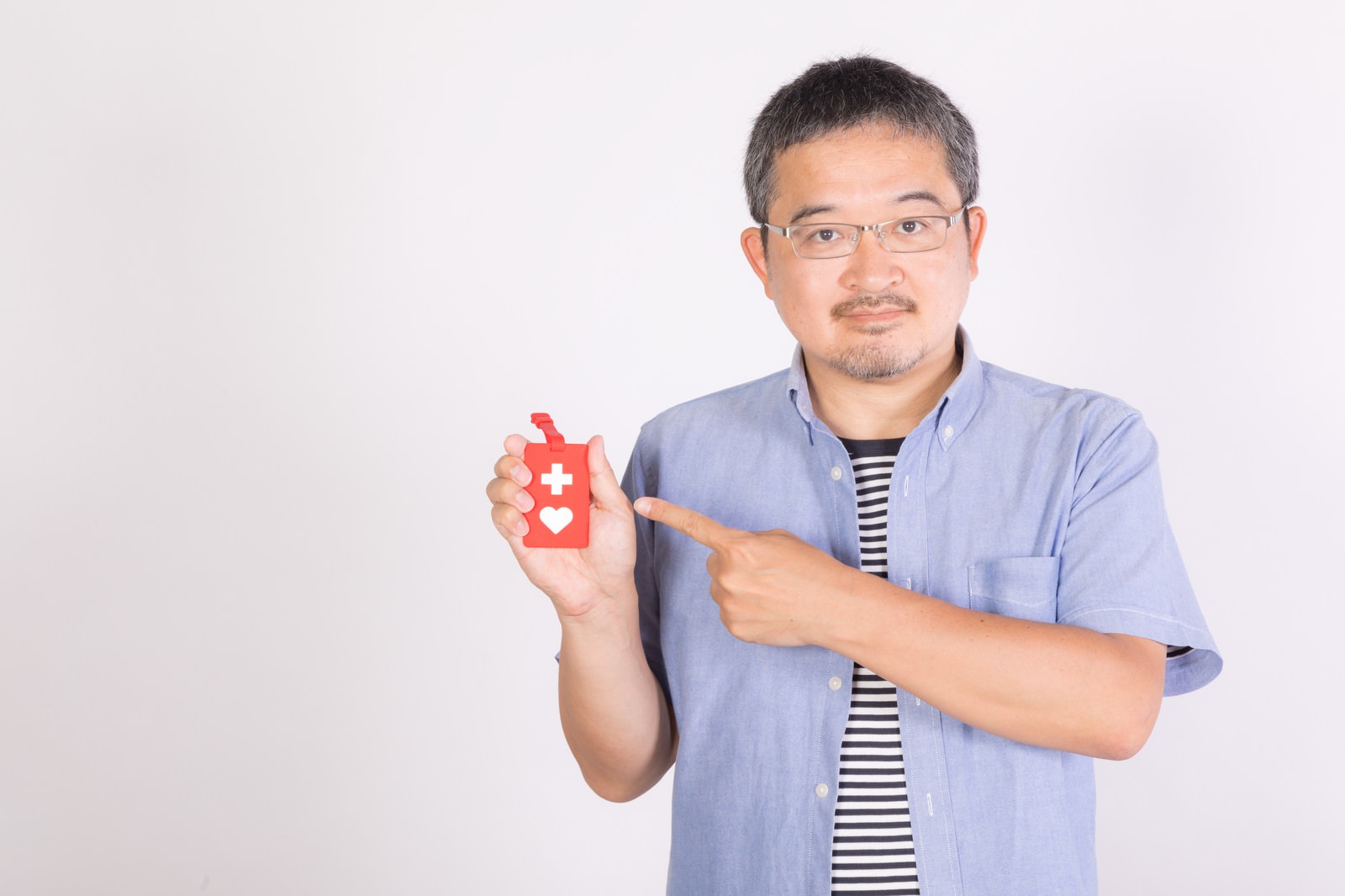 青いシャツを着た男性がヘルプマークを手に持って示している様子［モデル：ナリシゲ］