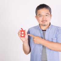 ヘルプマークを手に持って示す男性の障害者支援啓発の写真