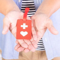 赤いヘルプマークを両手で大切に持って差し出す所持者の写真