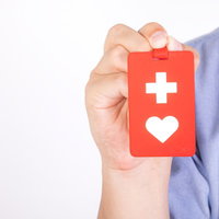 赤いヘルプマークを手に持って掲げる男性の支援姿勢の写真