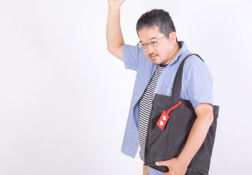 ヘルプマークを持つ体調が優れない男性が苦しい表情