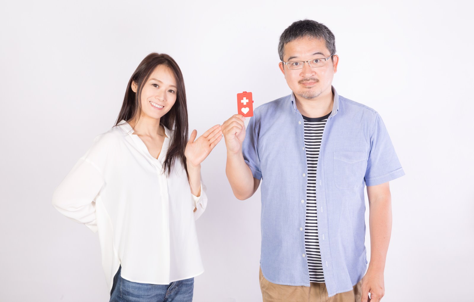 白い背景でヘルプマークを持つ男性と隣に立つ女性［モデル：土本寛子 ナリシゲ］