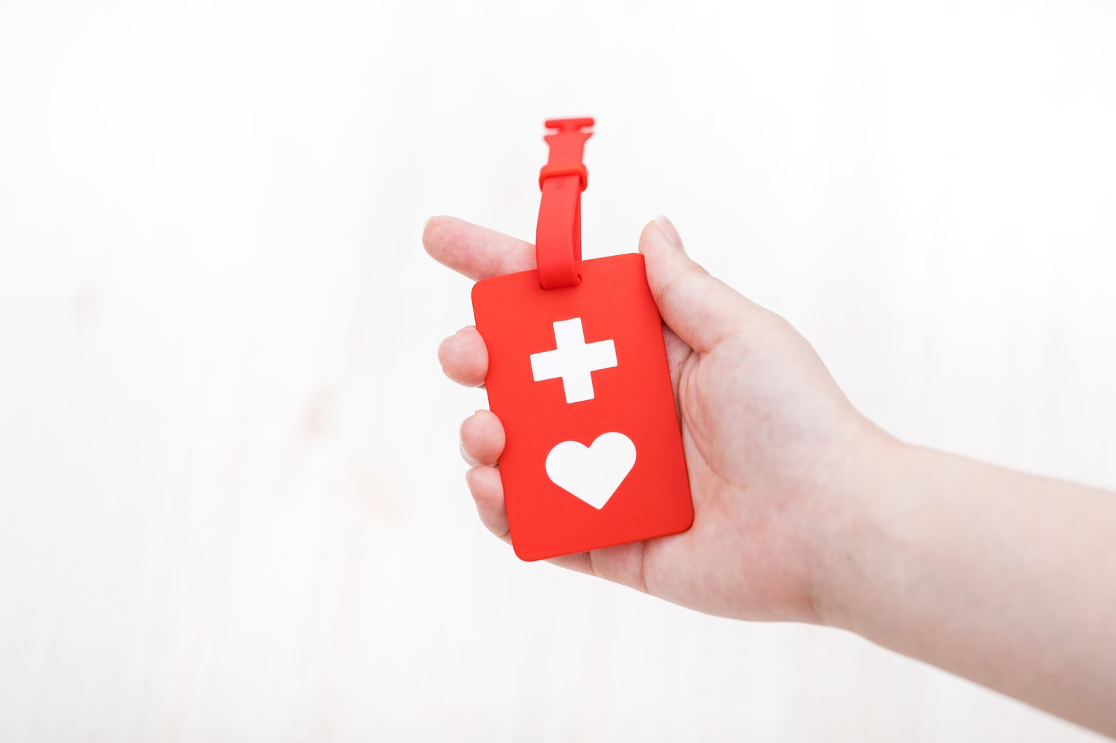 右手で赤いヘルプマークを持っている様子