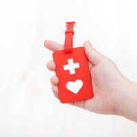 右手に持った赤いヘルプマーク、障害者支援と心配りを示す公共交通機関での配慮啓発の写真