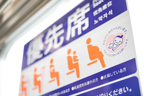 電車内の優先席に掲示されたマタニティマークとヘルプマーク