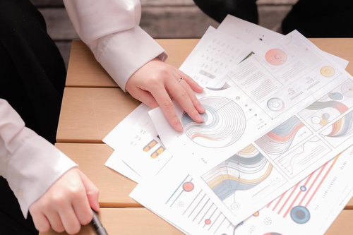 テーブルに広げたグラフや図表が書かれた資料を指で確認