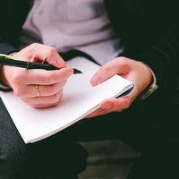メモ帳に書き込むビジネスマンの手元の写真