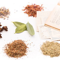 乾燥ハーブと漢方薬の粉末が並ぶ古書とのスタイリングの写真