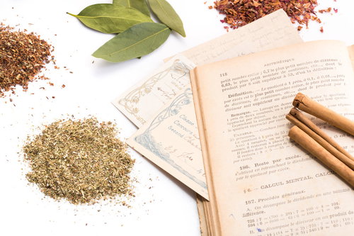 白い背景に配置した乾燥ハーブと古書、シナモンスティック