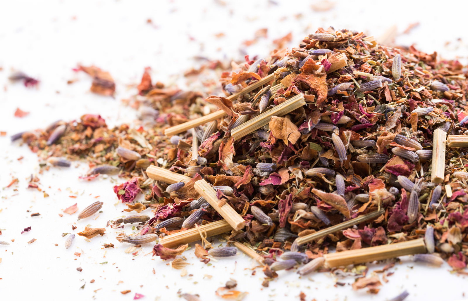 白い背景に散らばった茶色や赤茶色の乾燥ハーブの葉と茎