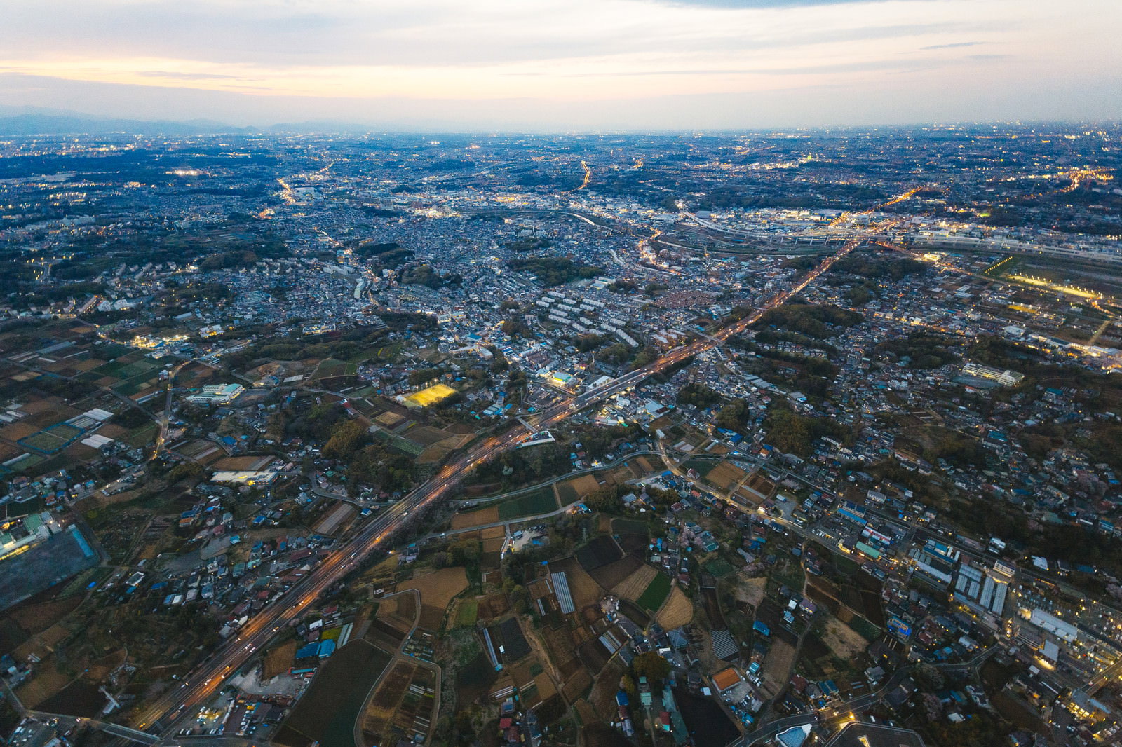 夕暮れ時の上空から撮影した街並みと高速道路の風景
