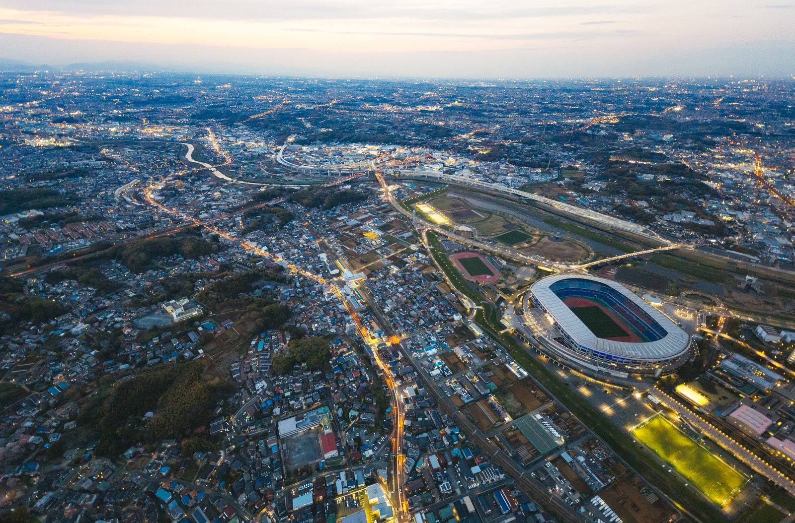 日産スタジアム上空からヘリ空撮した夕暮れの新横浜エリアの街並み