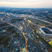 ヘリ空撮で捉えた日産スタジアム上空の夕暮れ景観の写真
