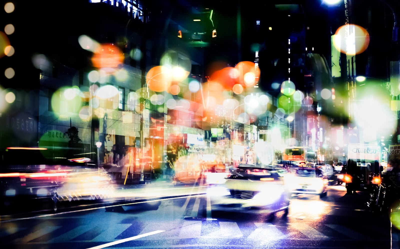交通量の多い夜の街をフォトモンタージュで表現し、信号機の光と車のライトが光跡と玉ボケで重なる写真素材