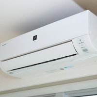 新調したホワイト家電のエアコン、壁掛けタイプの冷暖房空調設備の写真