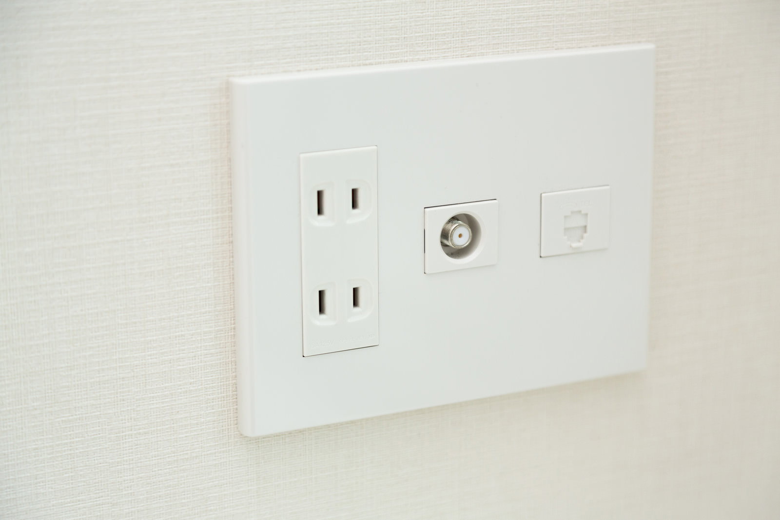 白い壁に設置された電源コンセントとアンテナ端子のプレート