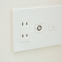 白い壁に設置されたTVのアンテナ端子とコンセント差込口の写真