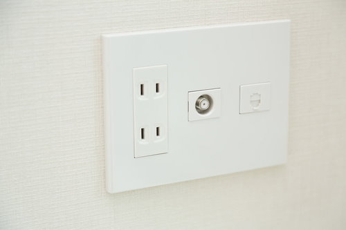 白い壁に設置されたTVのアンテナ端子とコンセント差込口