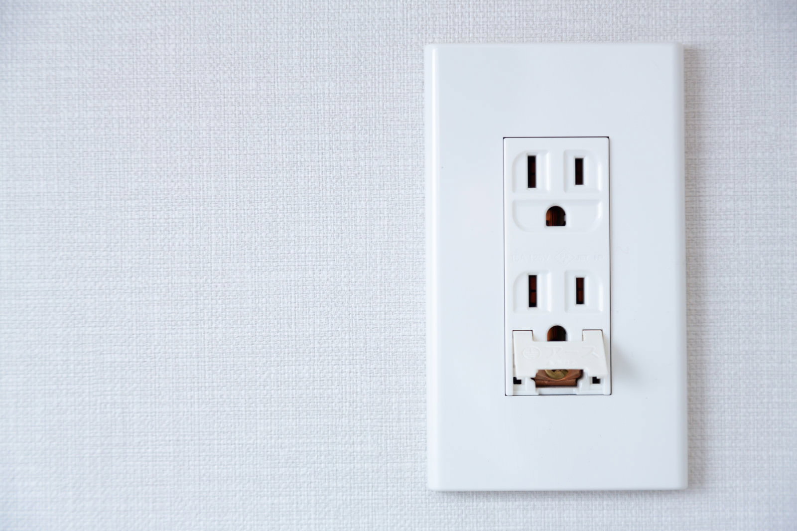 白い壁に設置された標準的な家庭用電源コンセント
