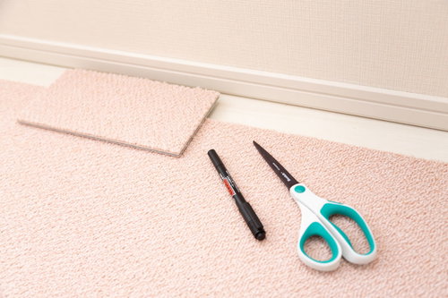 ピンク色のタイルカーペットを隙間部分に合わせてハサミで切る