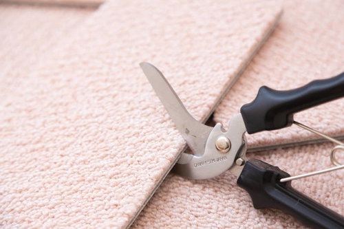 ベージュ色のカーペットを万能ばさみでカットする絨毯施工