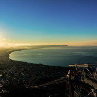 展望台の手すり越しに見える湾岸都市の初日の出風景の写真