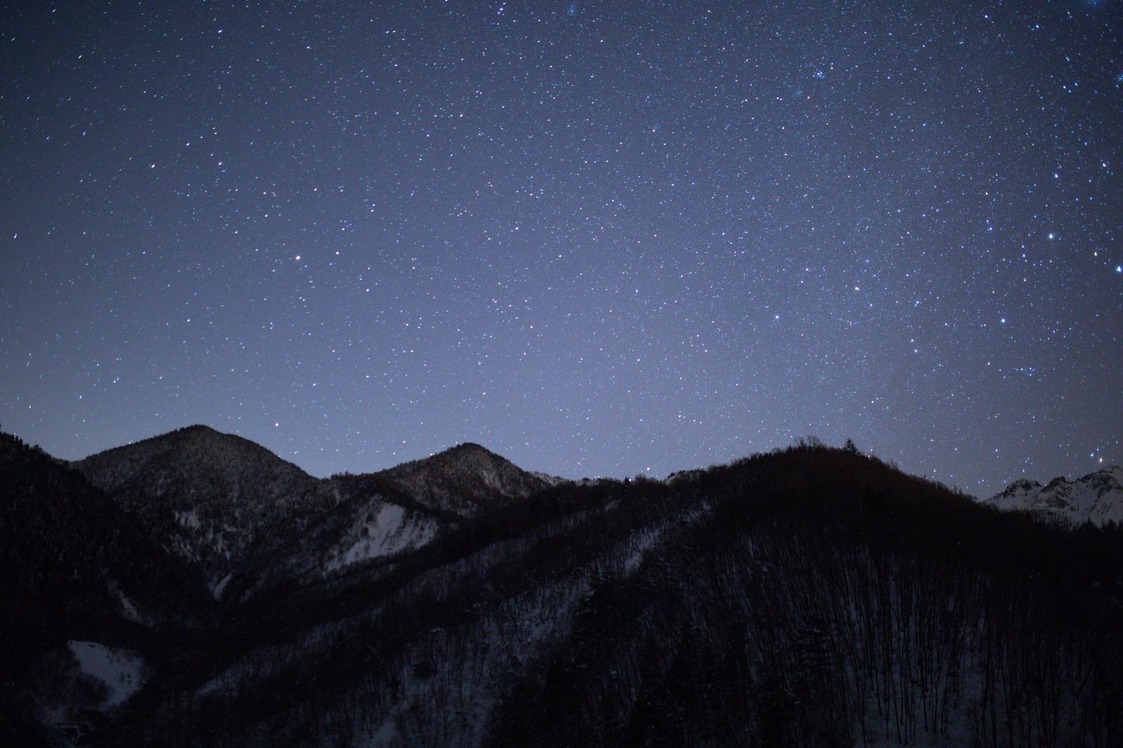 雪の山々のシルエットに無数の星が輝く夜空