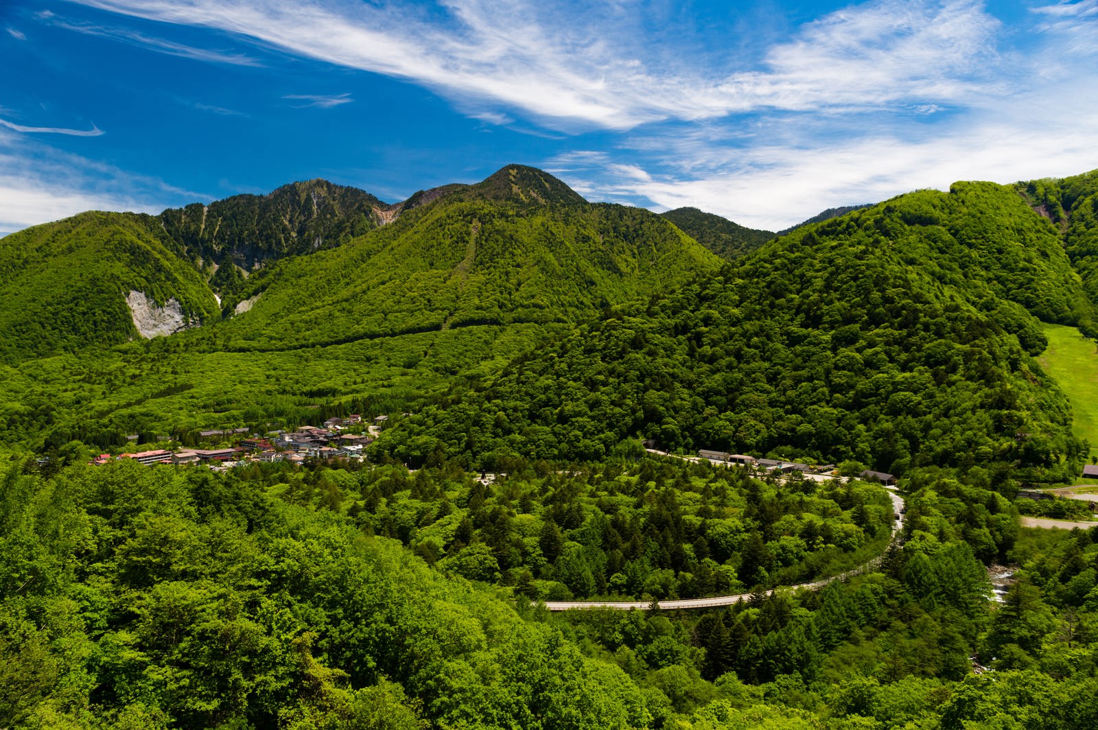 158号線から見下ろす平湯温泉街の全景。緑の山々に囲まれた谷間に温泉街が広がる