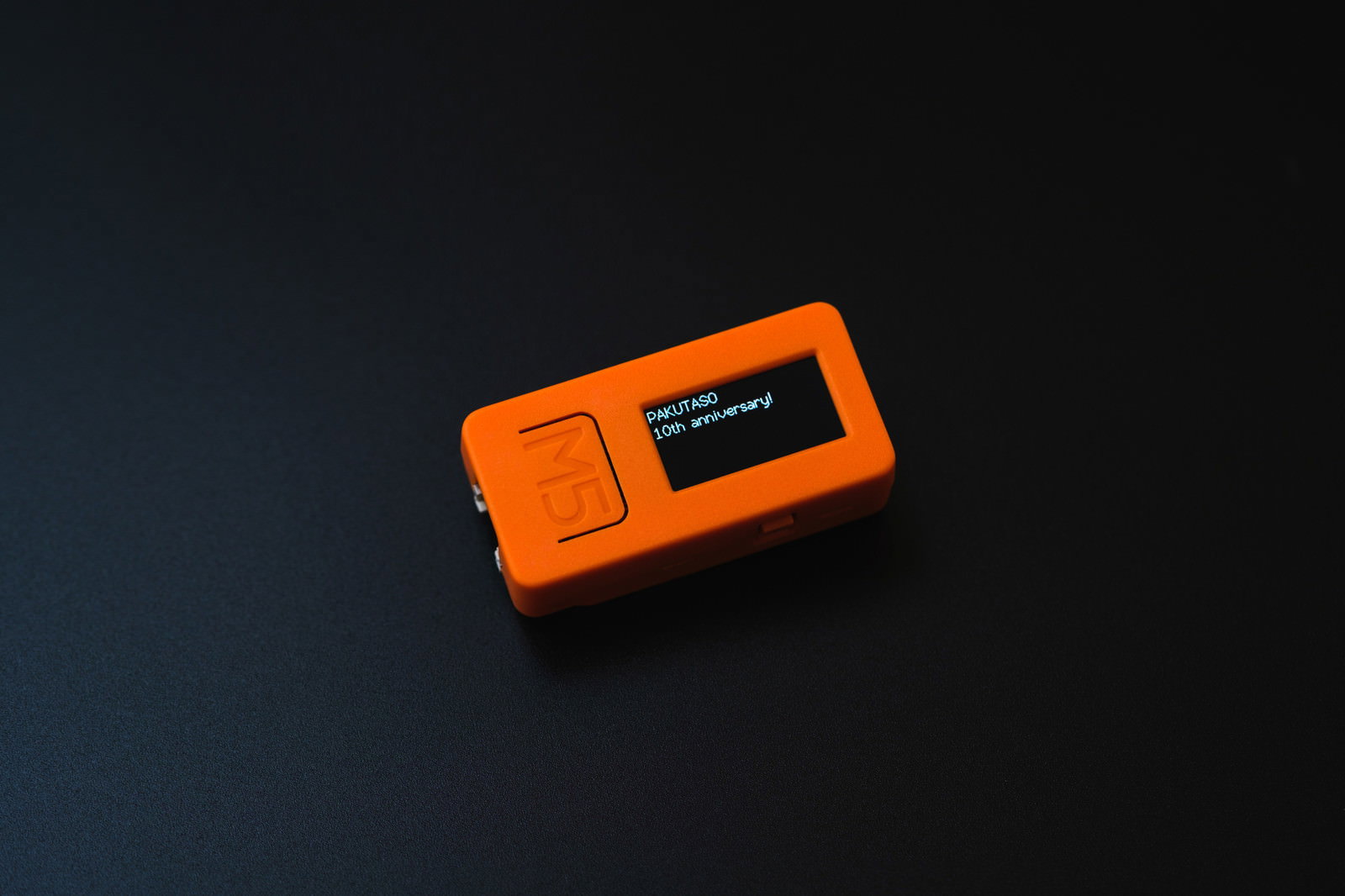 オレンジ色のIoT開発基板M5Stackが暗い背景に置かれている