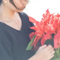 赤いポインセチアの花束を抱える女性の横顔の写真