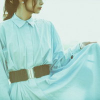 水色のシャツとスカートのすそを持つ女性の横顔ポーズの写真