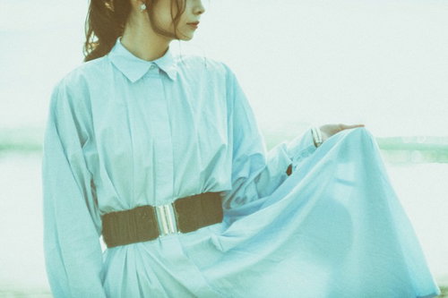 水色のシャツとスカートのすそを持つ女性の横顔ポーズ