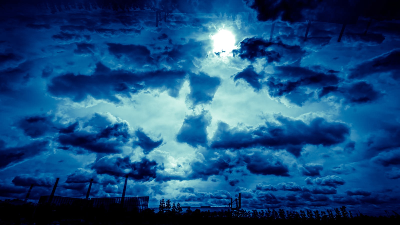 濃紺の雲の間から太陽の光が差し込む空
