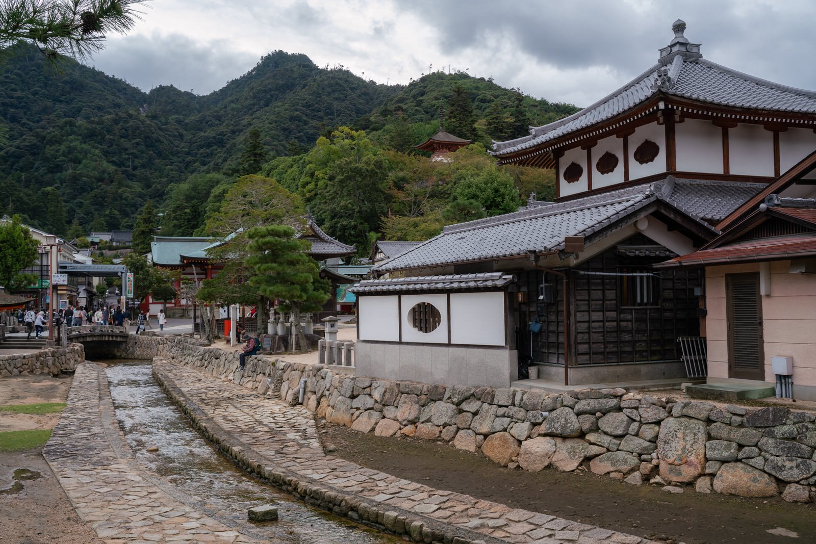 厳島神社の境内を流れる水路と伝統建築、背景の山々