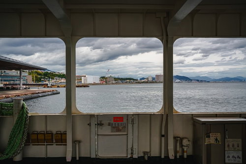 フェリー船のデッキからの港と山並みの景色
