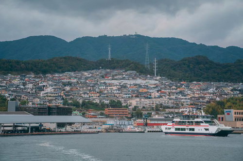 広島の港から出港するみせん丸と港町の風景の写真
