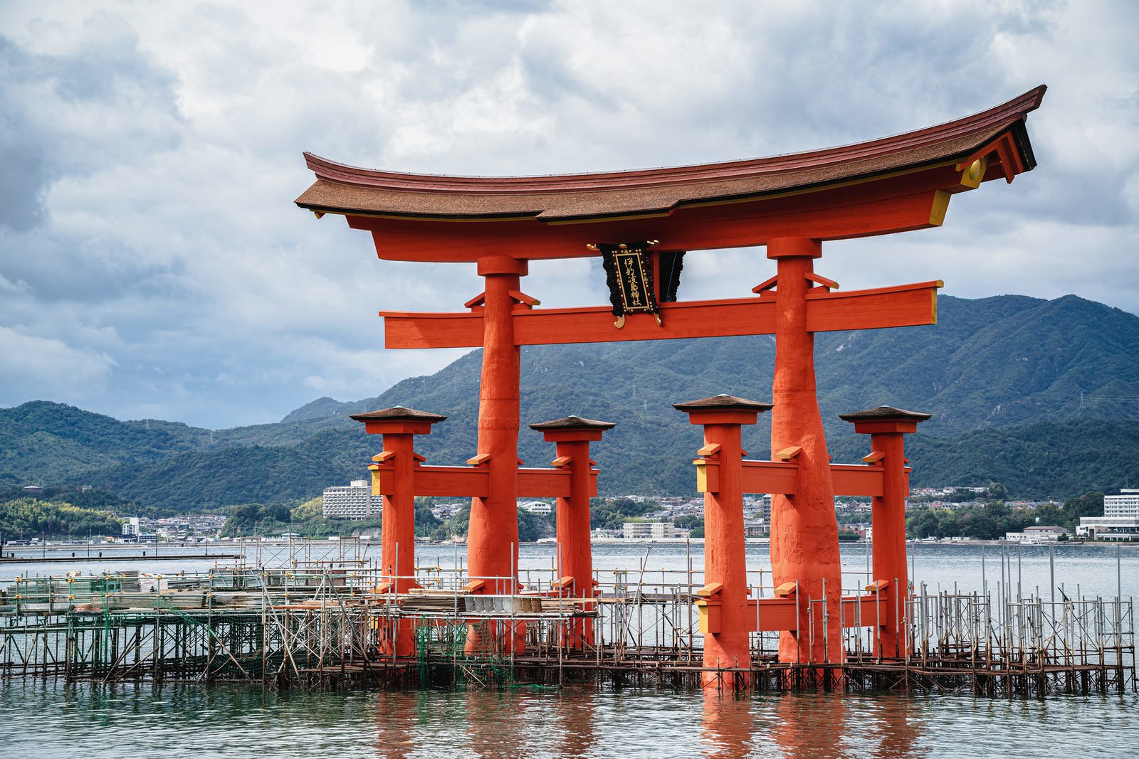 海に立つ厳島神社の朱色の大鳥居、背景には青空と雲